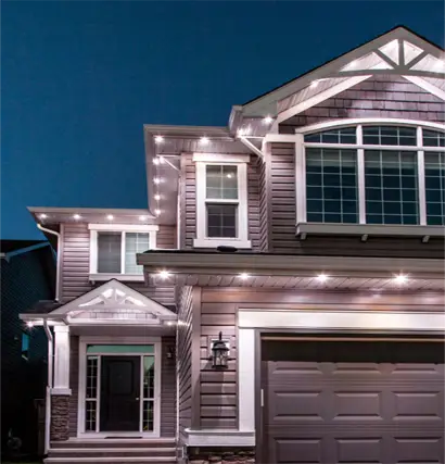 Modern suburban home with elegant architectural Gemstone track lighting accentuating the roofline, windows, and entryway at night.