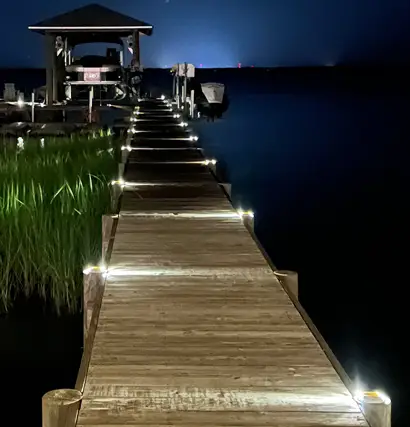 Wooden boat dock with LED pathway lighting providing safe and stylish illumination over the water at night.