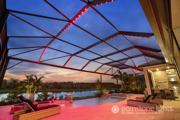 Red LED lighting on a modern screened pool enclosure at sunset