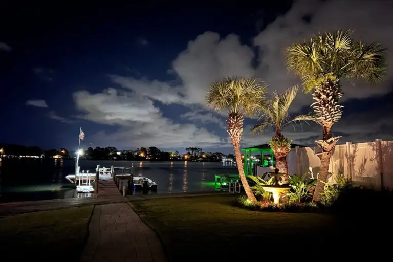 Palm trees and a waterfront boat dock illuminated by LED landscape lighting installed by Emerald Coast Illumination in Destin, Florida