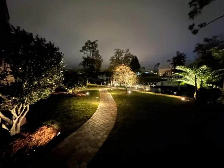 Garden with curved walkway and path lights outside an orange stucco house