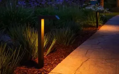 FX Luminaire MP-30 modern path light illuminating a mulched garden bed and walkway
