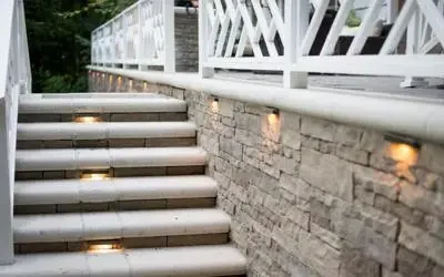 FX Luminaire step and wall lights illuminating a stone stairway and white deck railing