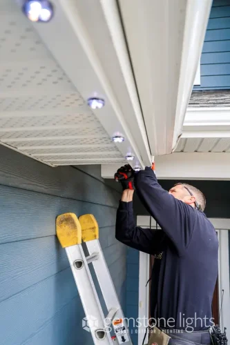 Technician installing permanent Gemstone Lights LED system on home soffit