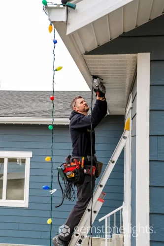 Worker on ladder installing Gemstone Lights permanent LED track lighting