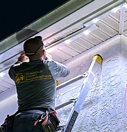 Installer on the ladder installing Gemstone LED lights on house exterior.
