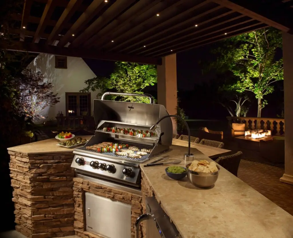 Outdoor kitchen with grill, bar seating, and ambient lighting for evening barbecues