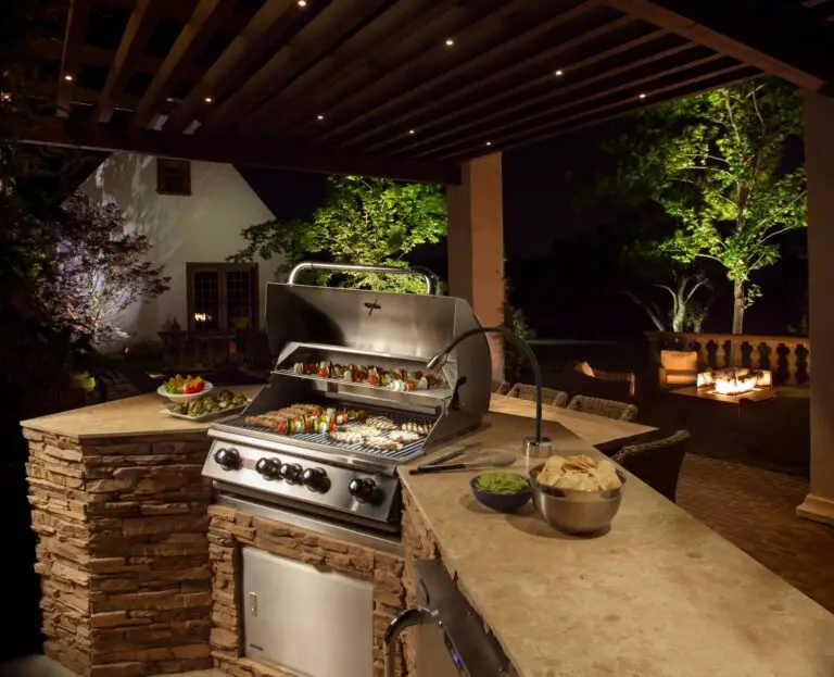 Outdoor kitchen with grill, bar seating, and ambient lighting for evening barbecues