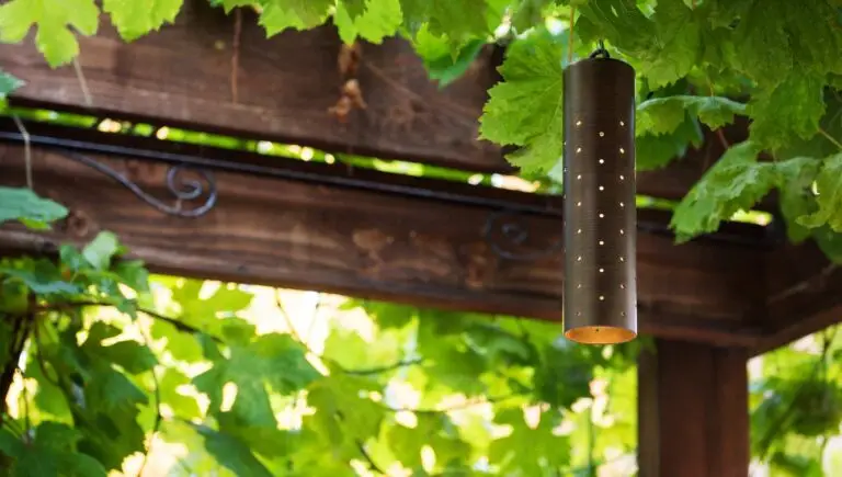 FX Luminaire LC pendant light installed under a pergola surrounded by greenery