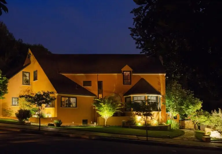 Yellow stucco home with architectural lighting in the front yard
