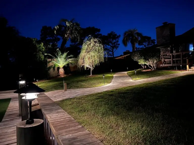 Palm trees and curved brick path illuminated at night with copper fixtures