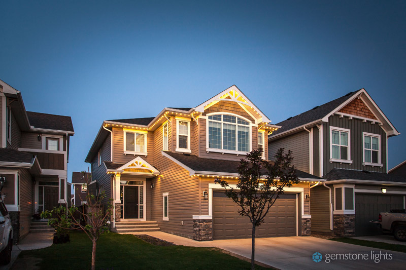 Two-story home enhanced with white Gemstone Lights outlining the roofline and entryway - after.