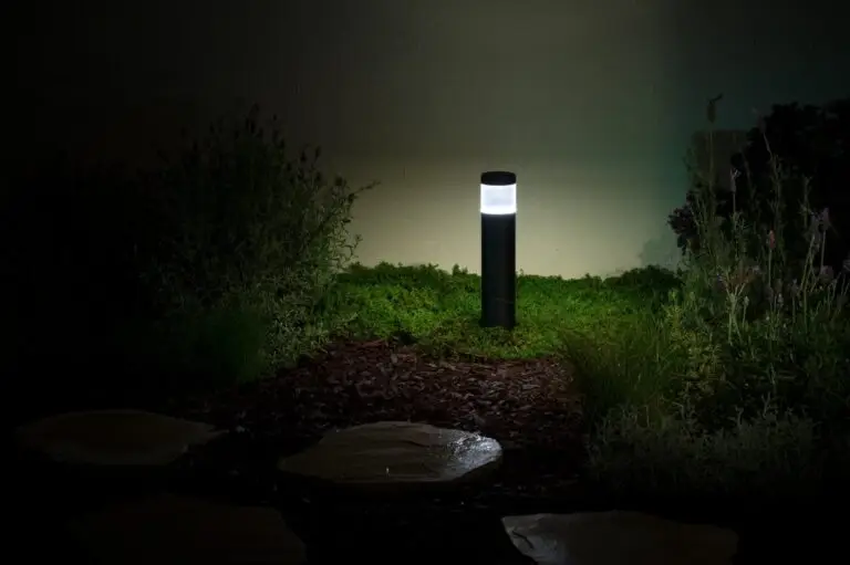 Modern black bollard-style garden light illuminating surrounding plants