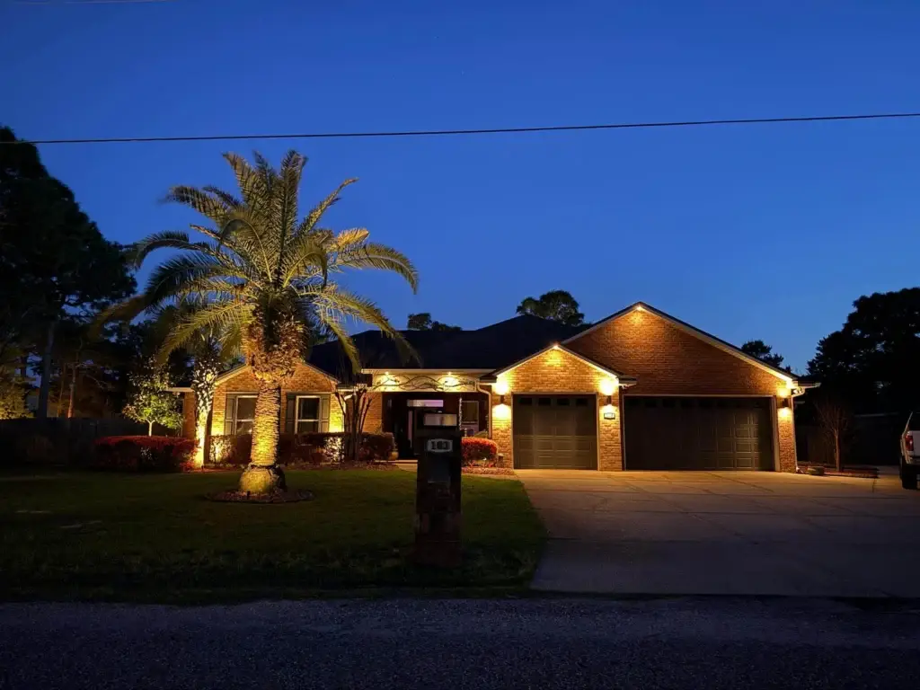 Panama City landscape lighting on a brick home, palm trees and yard.