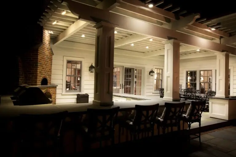 Covered patio with built-in ceiling lights and wall sconces providing warm, ambient outdoor lighting