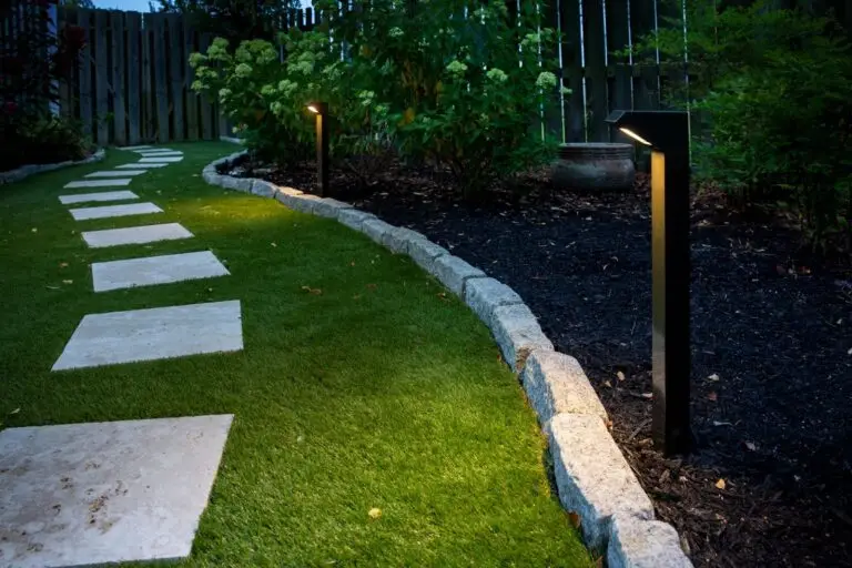 Evening view of pathway and garden lighting along a waterfront home’s driveway