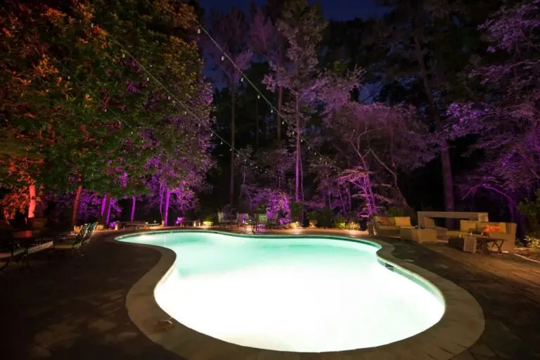 Color-changing LED lights illuminating trees and poolside patio at night in the Florida Panhandle